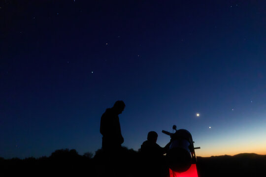Amateur astronomers observing stars, planets, Moon and other celestial objects with a telescope in nature.