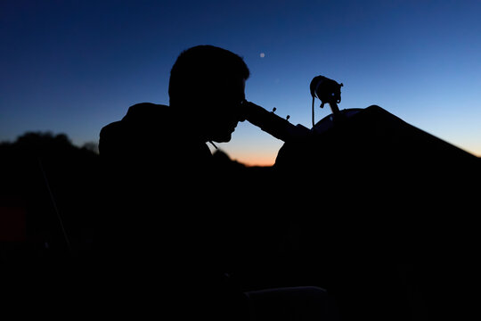 Amateur astronomer observing stars, planets, Moon and other celestial objects with a telescope in nature.