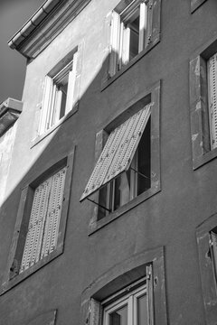 Black and white shot of a house facade with outward-opening shutters.