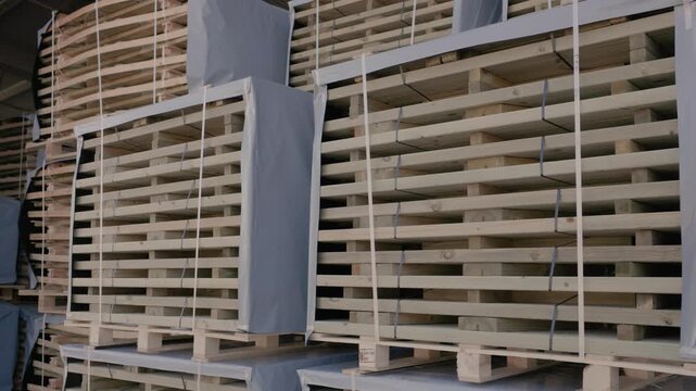 Large strapped stacks of wooden boards stored on pallets in an industrial warehouse