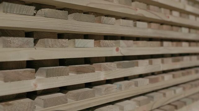 Close-up of stacked wooden boards with visible grain and spacers in a lumber workshop