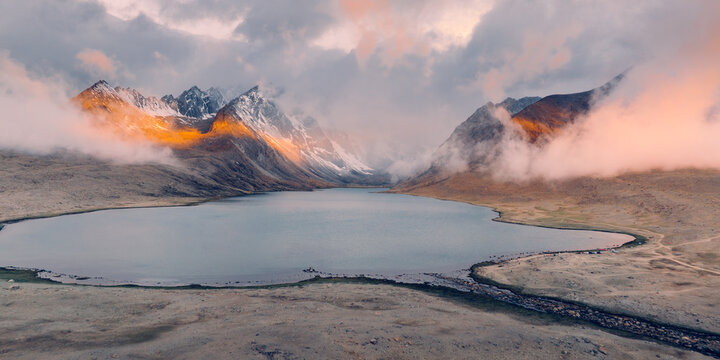 Morning sunlight breaks through heavy clouds, casting a remarkable ribbon of orange light across the mysterious Ama Drime.