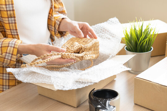 Online seller store, small business entrepreneur asian young woman, girl hand packing order product package, craft bag in box at home office, preparing pack parcel sent to delivery company to customer