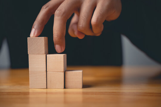 Sign of progress with a closeup of a man hand pose making a gesture up wooden blocks, a development sign showing career growth and business success on a wooden desk