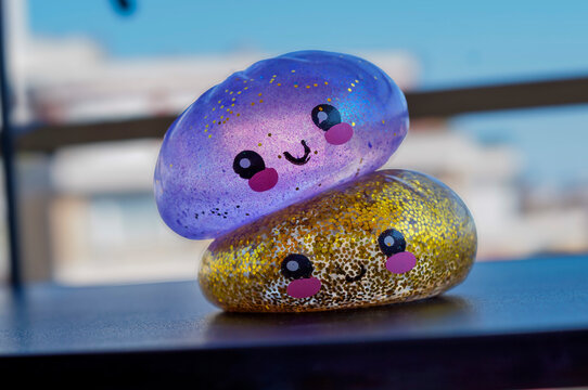 Two glitter squishy toys stacked on a table by a bright window. Playful sensory toy concept for children, stress relief, tactile learning and colorful childhood entertainment.