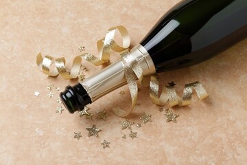 Fototapeta premium The Champagne Bottle Celebration with Ribbon and Star Confetti on Decorated Surface