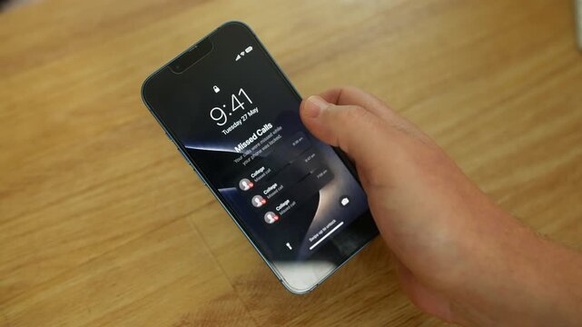 Missed calls from a College appear on a smartphone lock screen while being held over a wooden tabletop indoors. Mobile alerts emphasize student communication, enrollment updates, and urgent unanswered