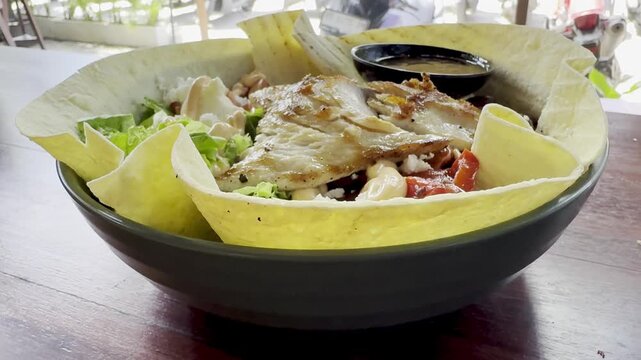 Appetizing burrito bowl featuring mahi mahi fish, rice, beans, capsicum, lettuce, feta cheese, and tortilla base, showcasing a colorful, nutritious meal perfect for healthy lifestyle content.