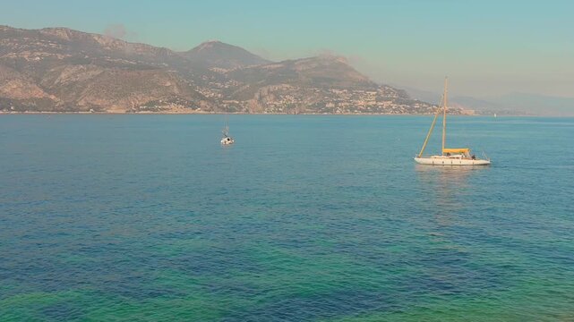 Aerial view of Mediterranean coastline with sailing fishing boat, Saint Jean Cap Ferra, France