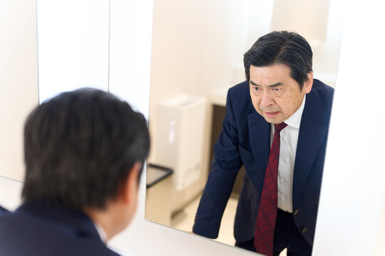 トイレの鏡で表情のチェックをするアジア人男性
