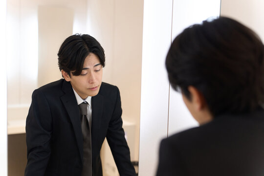 トイレの鏡で表情のチェックをするアジア人男性