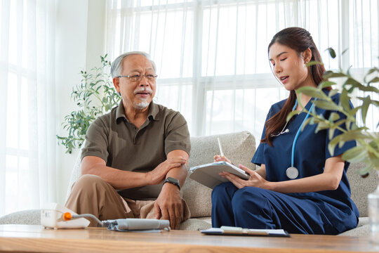 Female Nurse Conducting Routine Health Check for Elderly Man and Writing Notes on Tablet. Nursing at Home Scene with Senior Health Check and Tablet Note Taking by Caregiver.