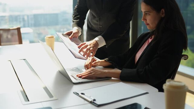 Senior manager discusses project issues with female employee during office meeting after unexpected setback. Professional feedback, performance improvement and problem solving in modern workplace.