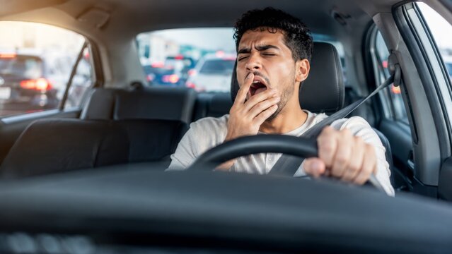 Tired man yawning while stuck in traffic. Exhausted driver covers mouth in car during commute. banner format