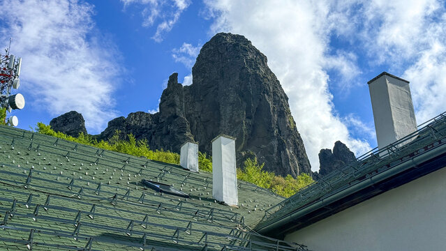 Rock outcrop above village roofs under spring clouds in crisp daylight suitable for editorial, travel, landscape, social media, Babin Zub Serbia