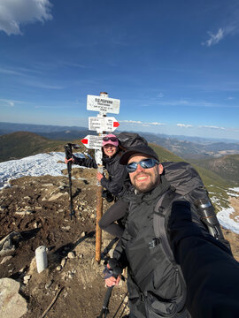 Happy hiking couple taking selfie at mountain trail signpost