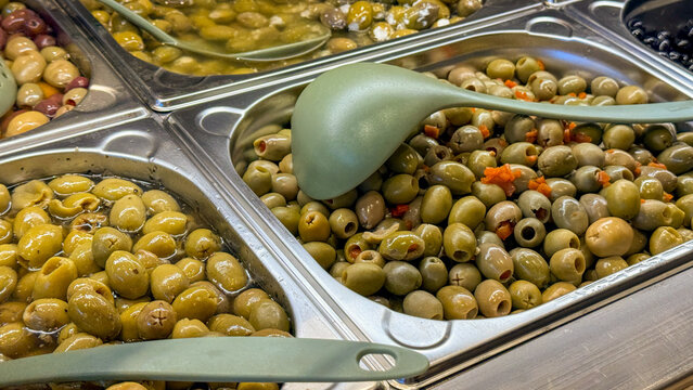 Colorful marinated olive bar in a deli with warm lighting perfect for food editorial, grocery ads, culinary blogs, recipe posts, social media, 5 May 2026 Subitica, Serbia