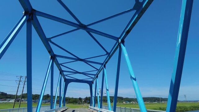 【4K】幾何学的な青いトラス橋を渡る車窓展望：迫りくる鉄骨の造形美。初夏の青空と近代インフラを駆け抜けるドライブ映像素材　[4K] Driving Through a Geometric Blue Steel Truss Bridge: POV Front Window View, Modern Infrastructure B-roll 撮影日：20260624-1

