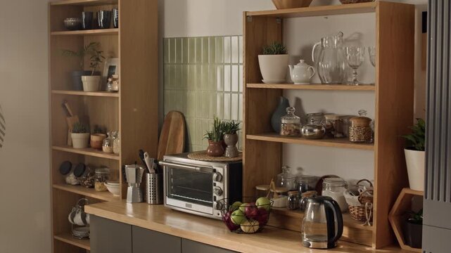 No people shot of kitchen counter displaying wooden shelves, electric kettle, toaster oven, and fresh apples. Clip serving as background for home appliance ads or interior design promotional videos