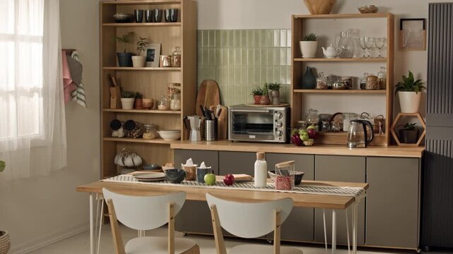 No people shot of modern kitchen interior showing dining table set for breakfast with shelves and appliances in background. Clip suitable for real estate promotion or interior design showcases