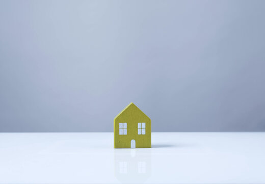 Single wooden house model on a blue background with copy space. Minimal real estate concept for home ownership, property investment, mortgage, home insurance, housing market, finance and residential b