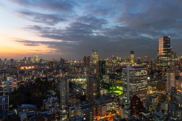 Fototapeta premium Modern Tokyo cityscape at dusk during the magic hour, featuring the illuminated Azabudai Hills skyscraper and surrounding city lights.