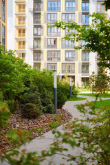 Fototapeta premium Modern residential complex with green spaces. Landscaping in the courtyard of an apartment building. Urban landscape.