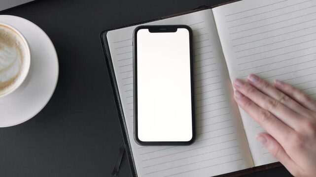 Smartphone mockup on notebook with coffee cup on desk