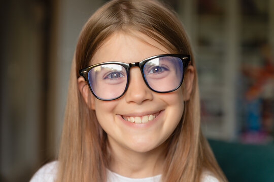 Close-up portrait of a smiling little girl wearing eyeglasses, representing education, healthy vision, learning, confidence, positive emotions, and happy childhood.