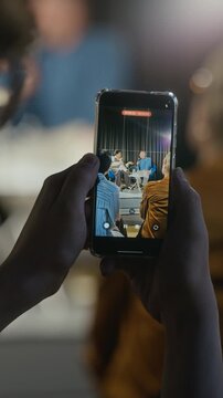 Vertical video of hands holding smartphone, recording panel discussion with speakers on stage during presentation. Footage is ideal for promoting public seminars or educational events