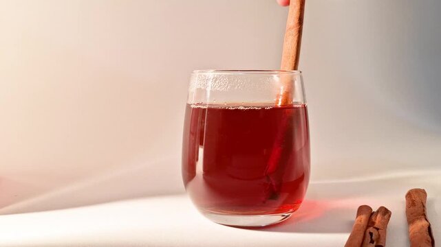 Warm herbal tea steeps with a cinnamon stick in a clear glass creating a cozy and aromatic beverage perfect for relaxation or a cold day