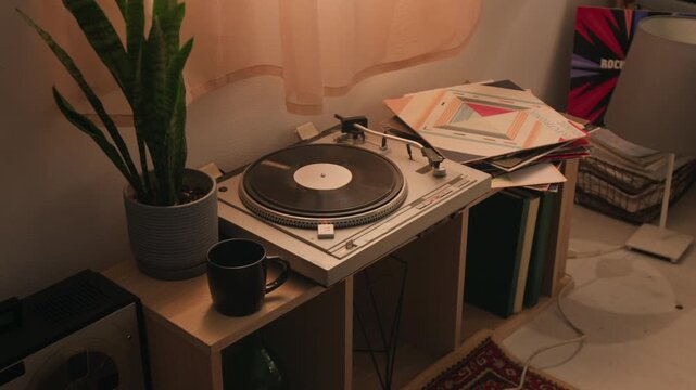 Vintage turntable spinning vinyl record on wooden shelf next to potted plant and mug. Visual for retro lifestyle commercials, music store advertisements, or home decor marketing campaigns