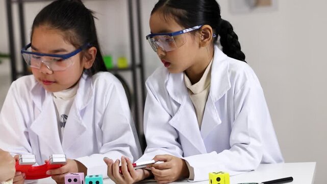 Two Young Asian Students Conducting Magnet Science Experiment in Classroom