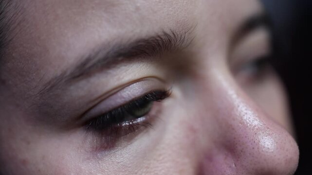 Detailed macro close-up of a woman's face as her expression shifts, eyes open and close in soft natural light. Captures emotion, skin texture, reflective moment. Perfect for human emotion videos
