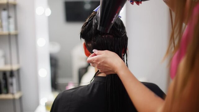 Hair stylist blow drying and finishing woman hairstyle in professional beauty salon focused on healthy hair elegant appearance and salon service. High quality 4k footage