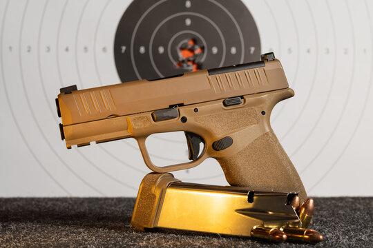Modern FDE tan striker fired pistol with loaded magazine and 9mm live ammunition rounds on shooting range table over paper target background showcasing precision training