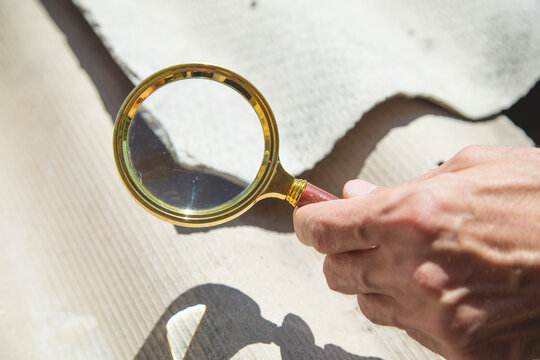 Male hand with a magnifying glass showing old asbestos roof. Health problems