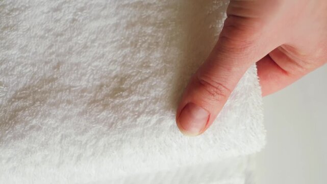 Close-up of maids hand folding and smoothing white towels in hotel room. Housekeeping service, clean linens, hospitality, cleanliness and professional hotel service concept. High quality 4k footage