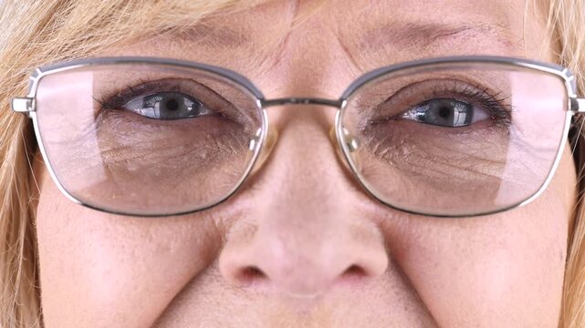 Close Up of Senior Woman Eyes Wearing Glasses. Extreme close up of senior woman eyes behind eyeglasses, showing wrinkles and mature skin in vision care, optometry and eye health concept.