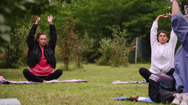 Women practicing yoga together with fitness trainer in the park enjoying stretching meditation balance and healthy outdoor lifestyle in nature. High quality 4k footage