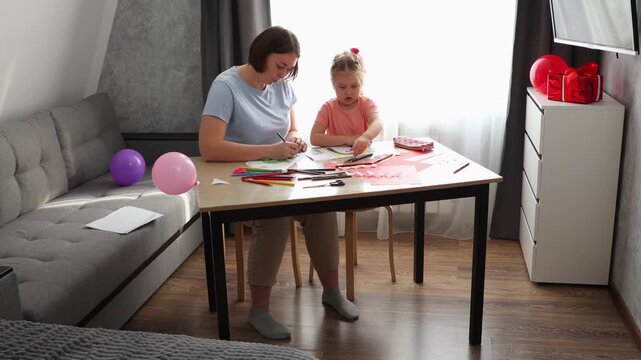 Mother and daughter spending time painting and designing handmade cards. Early learning, imagination, and bonding activity concept.