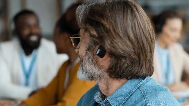 Cheerful customer service representative with a headset working in a busy call center with colleagues