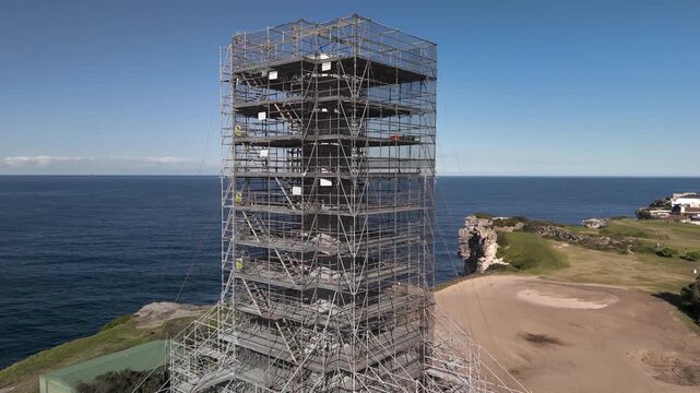 Old sewage tower in Bondi on a sunny day built in the early twentieth century under restoration. Camera orbits structure in CW direction revealing Pacific Ocean, beach and urban area.