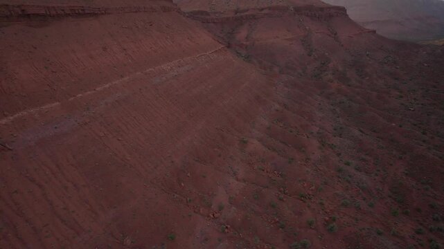Drone flying backwards filming mountains at moab at sunrise in 4k