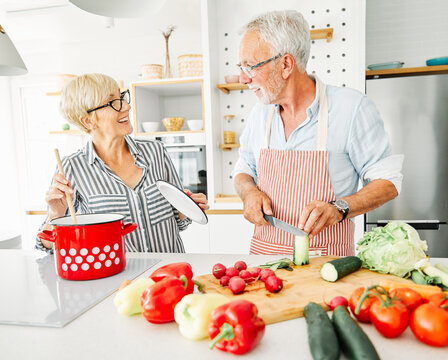 Portrait of happy senior couple prepering meal in kitchen
