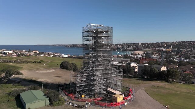 Old sewage tower in Bondi on a sunny day built in the early twentieth century and under restoration. Camera orbits structure in CCW direction revealing Pacific Ocean, beach and urban area.