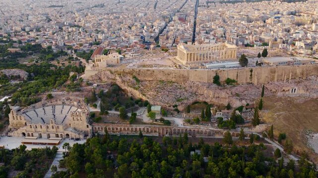 Majestic aerial view showing the historic acropolis with the parthenon temple and the odeon of herodes atticus, revealing the sprawling urban landscape of athens, greece at sunset