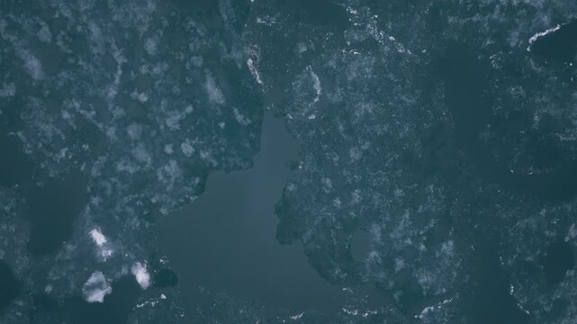 Abstract aerial view of melting ice fragments creating intricate patterns and textures across a mountain lake surface