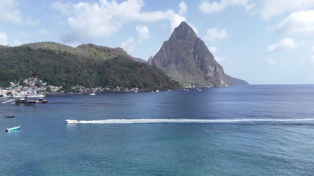 Scenic coastal drone flight pointing towards the grand Gros Piton volcanic mountain over the calm tropical sea in Saint Lucia