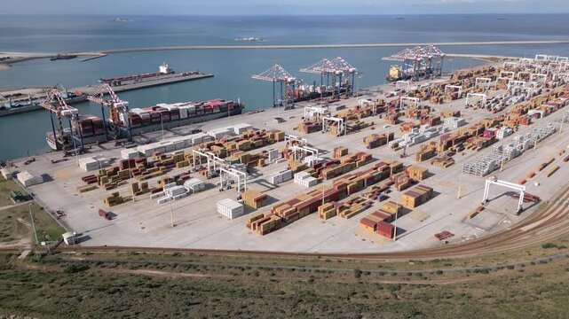 Rows of shipping containers, cranes and docked cargo ships fill a large South African port on a clear day.